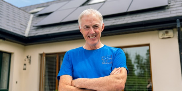 Man standing outside his house with solar PV on the roof