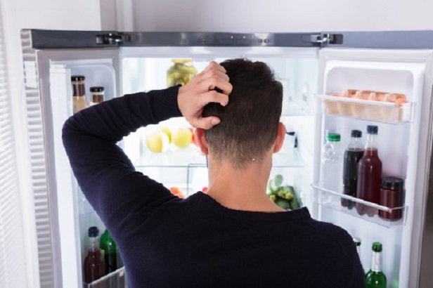 man looking into open fridge 