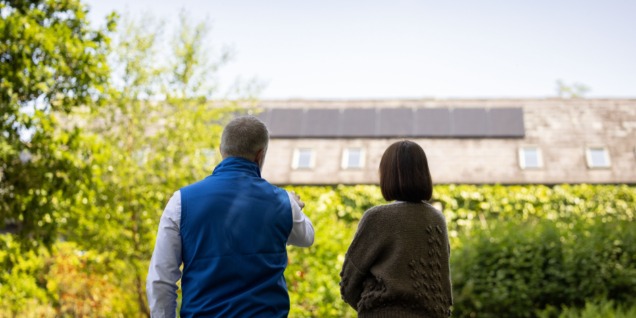 Electric Ireland staff and business customer looking at solar panels on roof